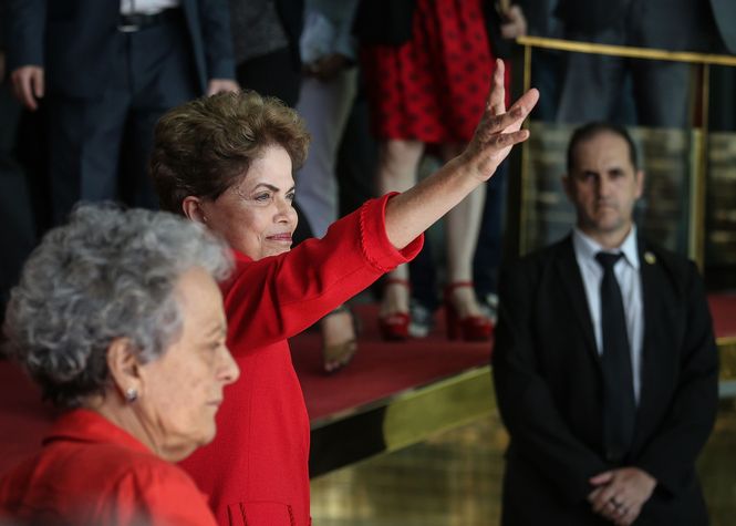 Dilma Rousseff winkt ihren Anhängern zu. Sie und ihre Parteikollegin tragen rote Kleider.