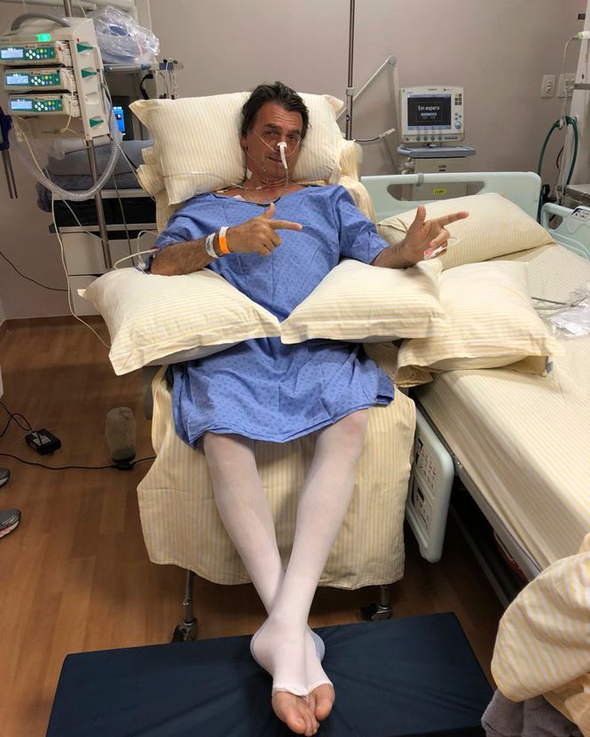 Jair Bolsonaro posiert nach dem Messerangriff auf ihn im Krankenhaus. Mit seinen Händen formt er ein Maschinengewehr. 