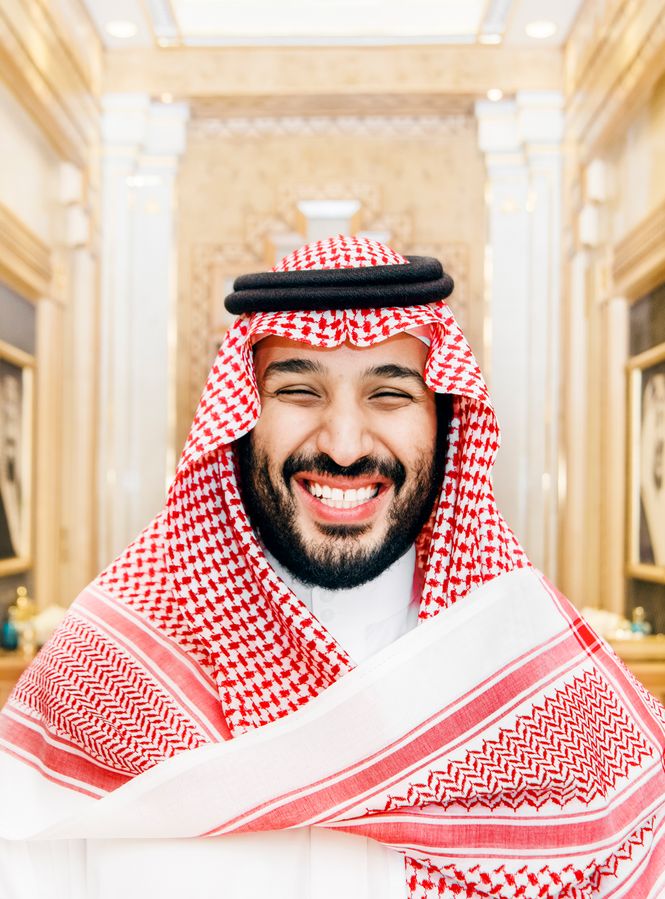 Ein grinsender Kronprinz im opulent geschmückten Gang der königlichen Wochenendresidenz. Das Porträt zeigt Muhammed bin Salman mit einer rot-weiss karierten Kufiya.