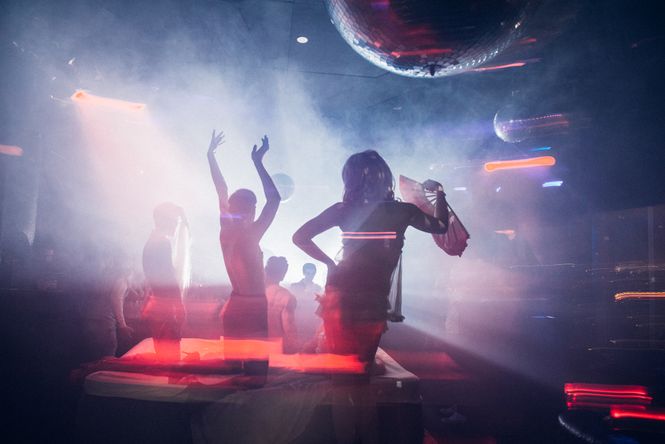 Partygäste tanzen unter Discokugeln.