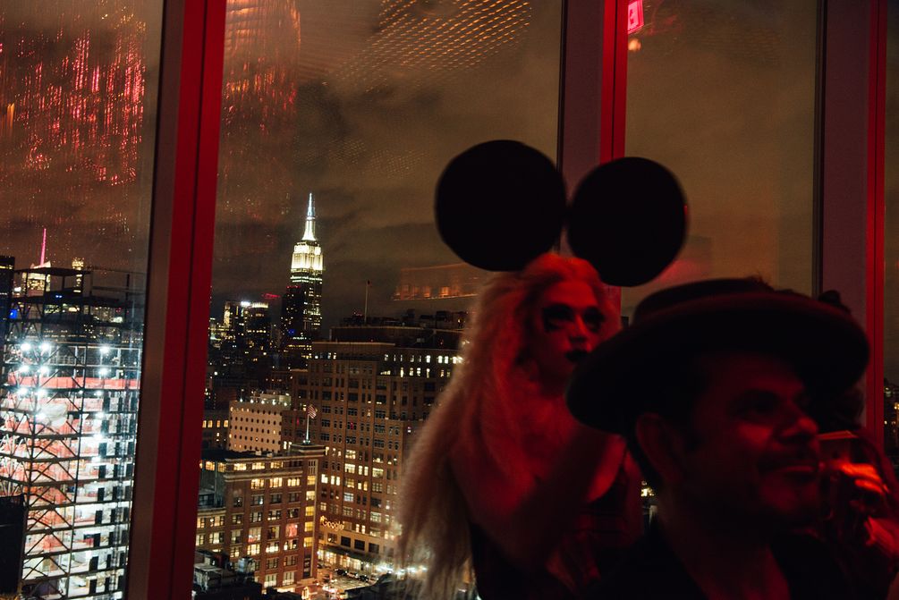 Partygäste vor der Fensterfront mit Aussicht auf das Empire State Building.