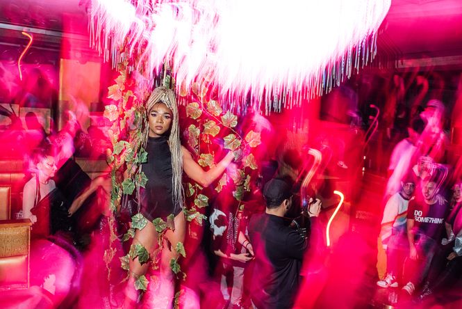 Pinke Lichtstimmung: Eine junge Frau mit blond gefärbten Zöpfen tanzt in der Partymenge..