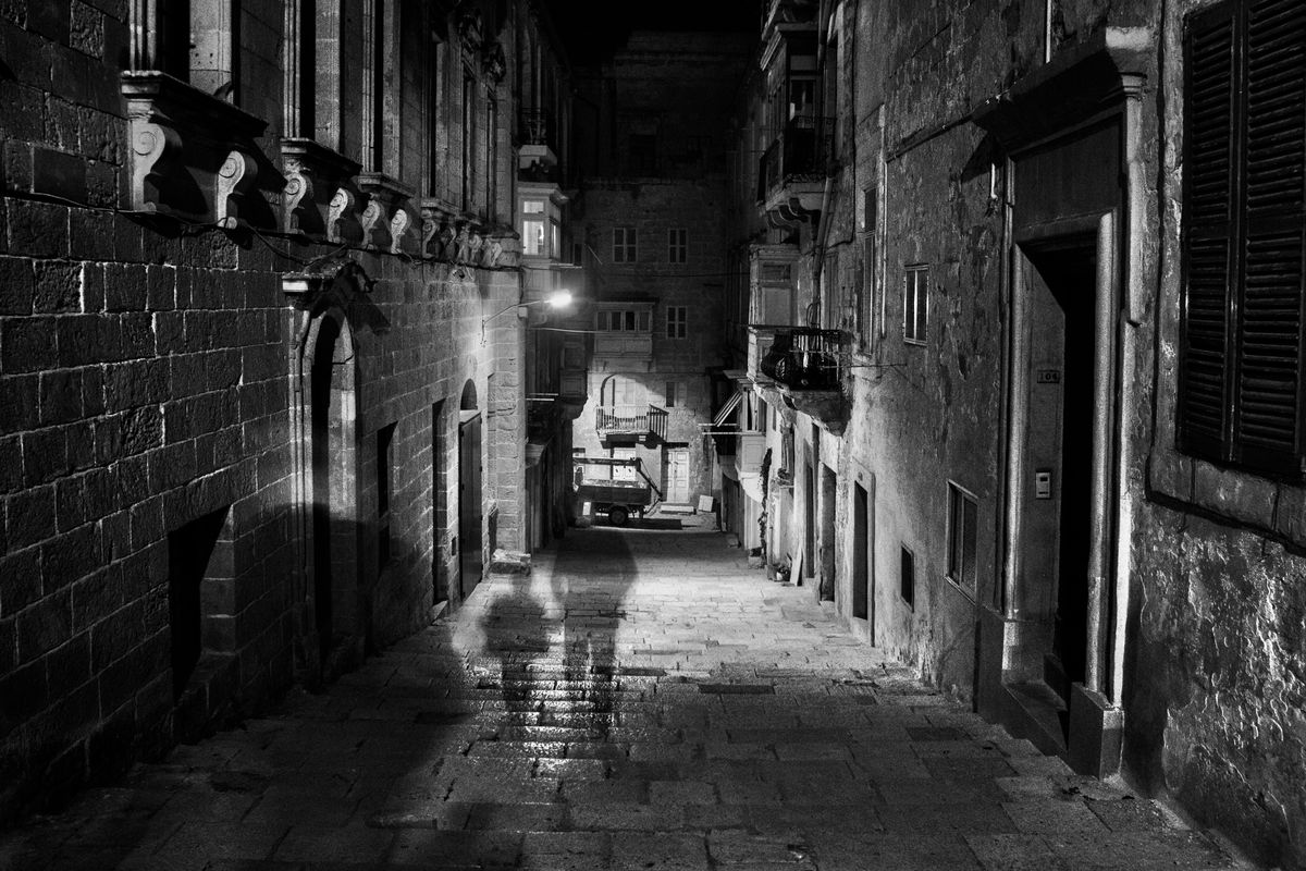 nächtliche Gasse in der Altstadt von Valetta, mit zwei schemenhaften Shilouetten