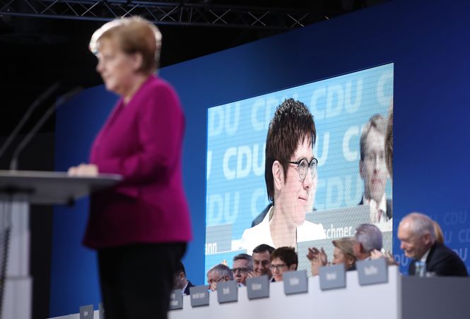 Angela Merkel am Rednerpult, hinter ihr auf einem Screen ist Annegret Kramp-Karrenbauer zu sehen 