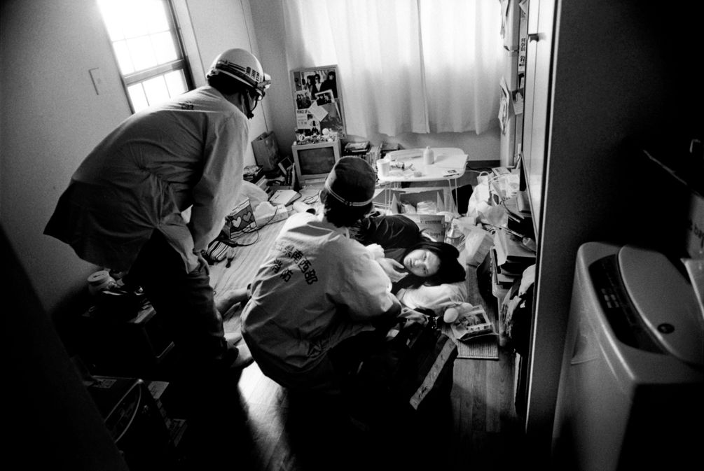 Kaori wird zuhause am Boden liegend von zwei Sanitätern betreut