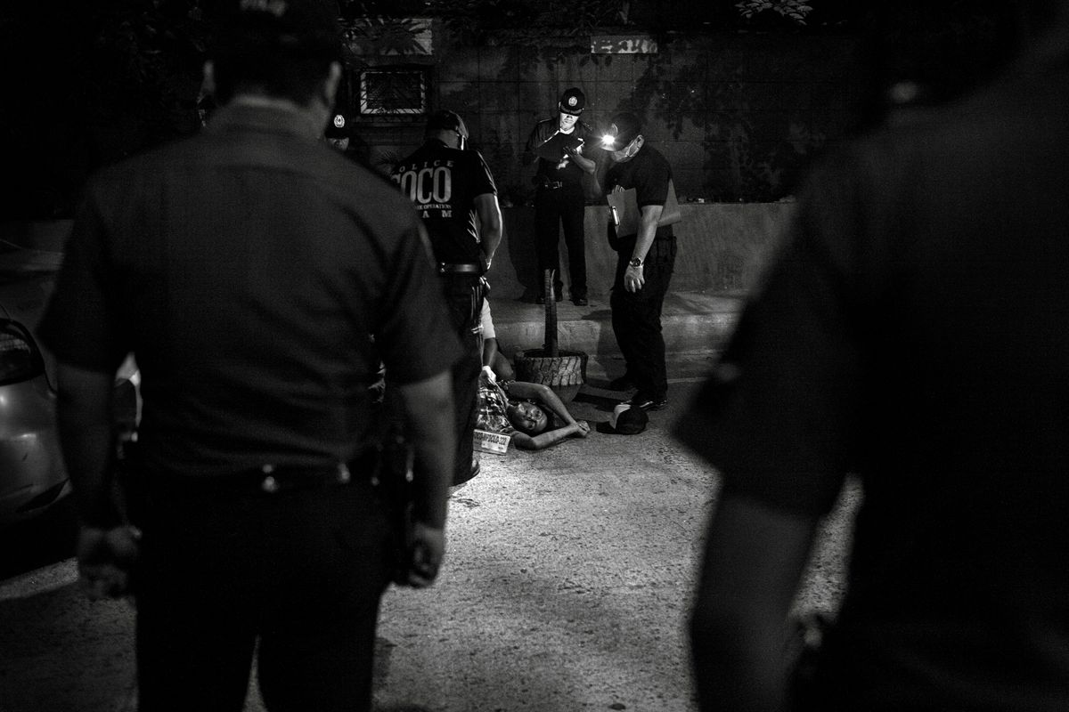 Polizisten beleuchten mit ihren Taschenlampen eine Leiche am Boden