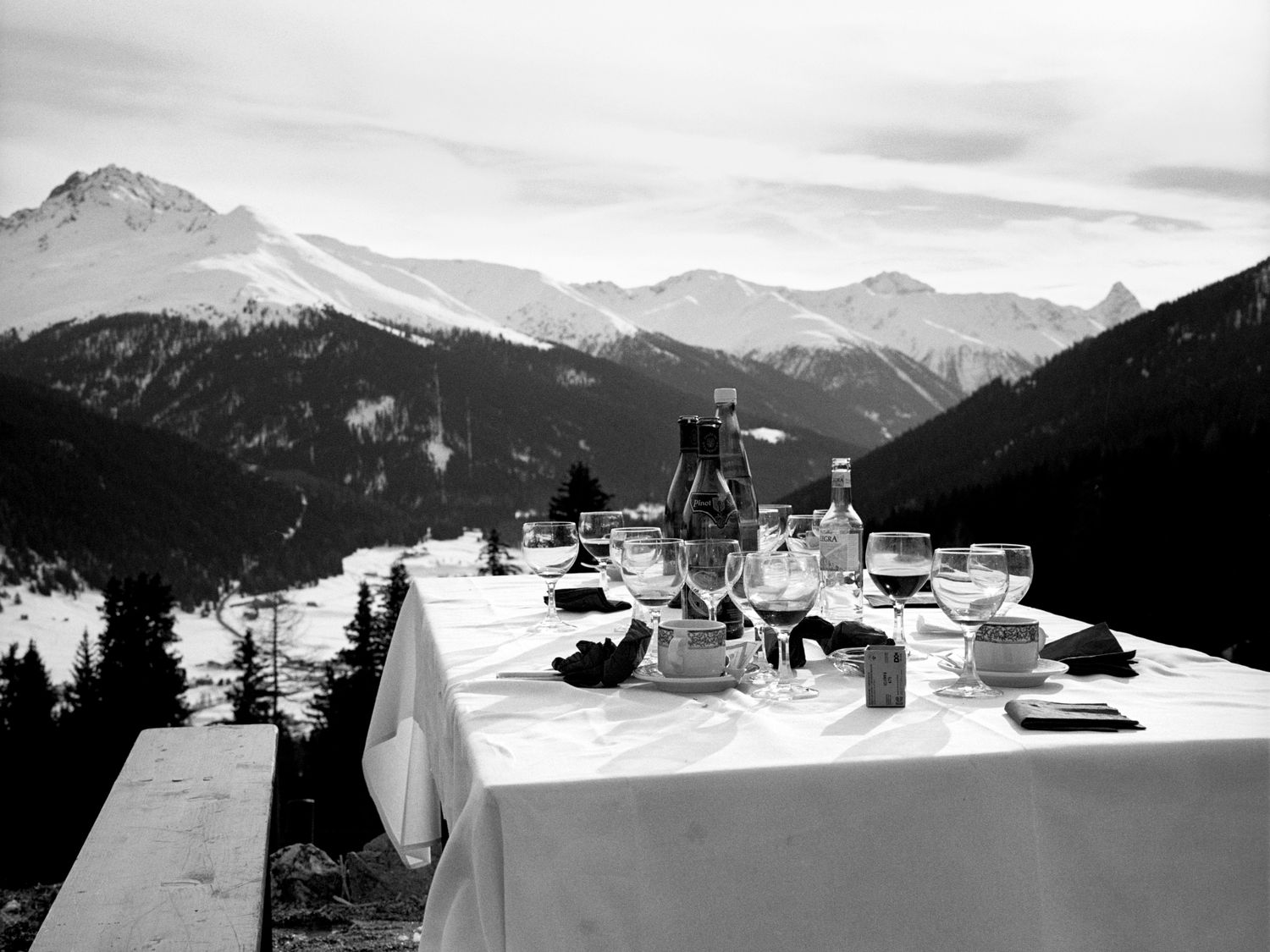 Tisch vor Bergpanorama mit leeren Weingläsern und Flaschen
