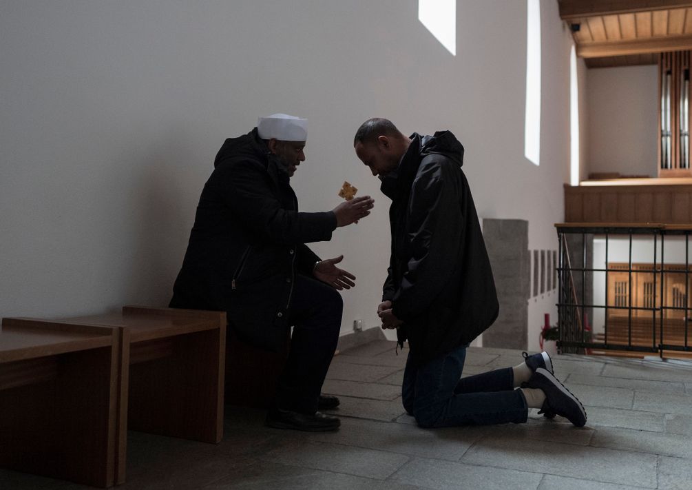 Priester Mussie Zerai betet mit einem Mann in der katholischen Kirche St. Luzi in Chur