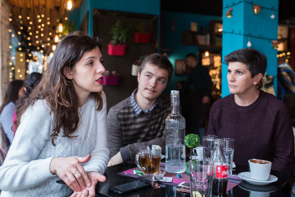 die drei Aktivisten sprechen miteinander in einem Cafe