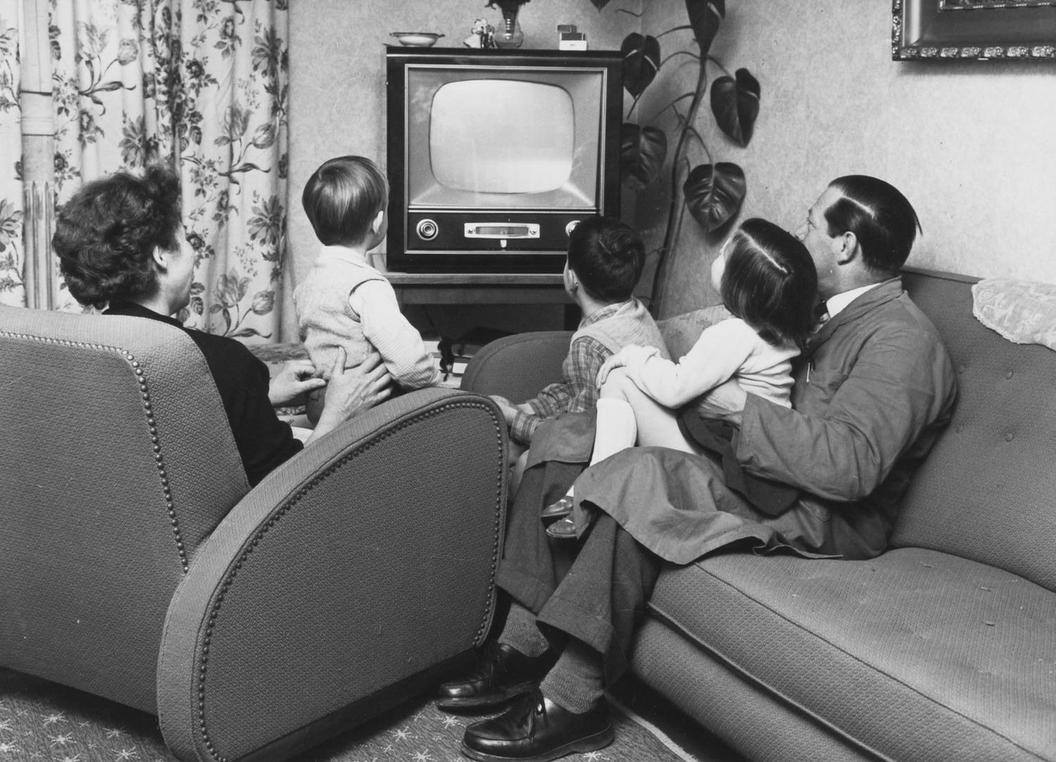 eine Familie im Wohnzimmer vor dem Fernsehen